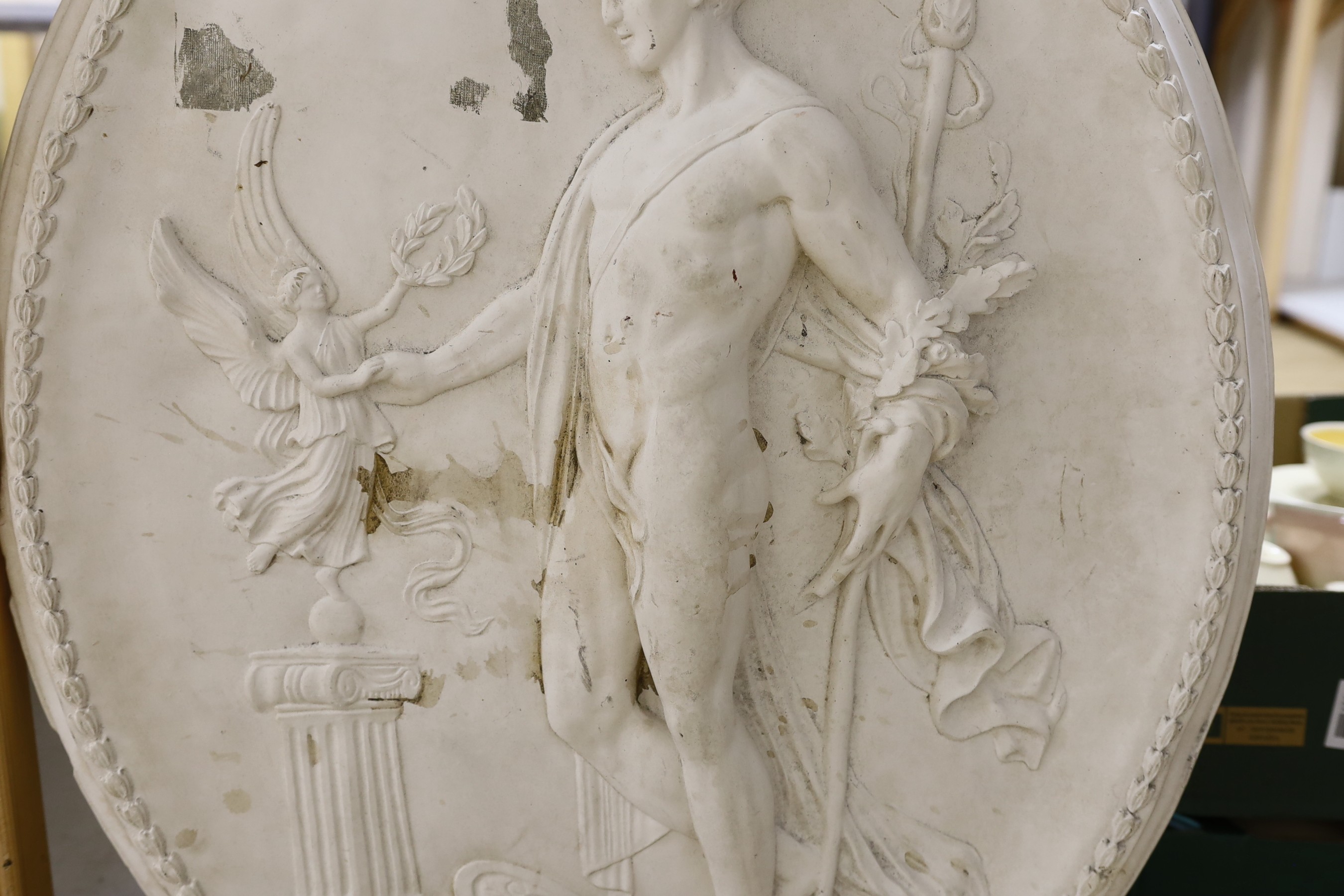 A cast plaster oval figural plaque